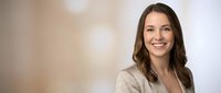 Young professional Caucasian businesswoman smiling confidently in modern office environment wearing beige blazer for corporate presentations and marketing.