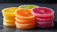 Fresh citrus fruit slices arranged in colorful stacks on dark surface. Orange, grapefruit and lime rounds create vibrant display for healthy eating concepts.