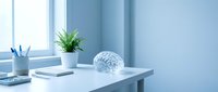 Modern minimalist office desk with brain model, plant and stationery in bright blue workspace for medical education, neuroscience research and healthcare concepts.
