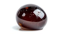 Smooth dark amber glass paperweight with trapped air bubbles and light reflections on white background, isolated decorative collectible art object.