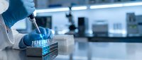 Laboratory scientist in blue gloves using pipette for sample analysis in modern research facility with equipment background for medical testing.