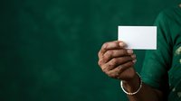 Hand holding blank white card against dark green background, suitable for business presentations, marketing campaigns, and promotional materials.