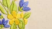 Colorful embroidered flowers with yellow and blue blooms on natural fabric background. Traditional needlework craft design for textile decoration projects.