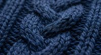 Navy blue cable knit wool sweater texture with intricate braided pattern closeup for cozy winter fashion and textile design backgrounds.