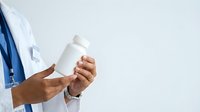 Doctor or healthcare professional with dark skin tone holding blank white medicine bottle for pharmaceutical advertising, medical promotion, or healthcare marketing purposes.