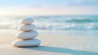 Zen stone stack on sandy beach with soft ocean waves creating peaceful meditation and balance concept for wellness and mindfulness practices.