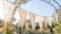 Vintage lace bunting flags hanging outdoors in soft natural light creating romantic atmosphere for weddings, parties and celebrations.