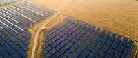 Aerial view of solar panel farm with organized rows of photovoltaic arrays on golden fields, renewable energy infrastructure for sustainable power generation.