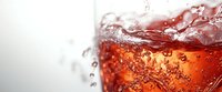 Refreshing cola drink with dynamic splashing liquid and fizzy bubbles in glass against light background, macro close up view for beverage advertising.