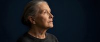Thoughtful senior Caucasian woman in profile gazing upward with hope and contemplation against dark background for aging and wisdom concepts.