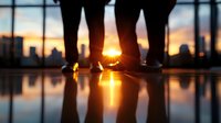 Silhouetted feet of couple standing together at sunset, dramatic orange sky reflection on wet surface creates romantic urban rooftop atmosphere.
