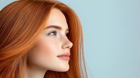 Young redhead woman with freckles and natural makeup in profile view against light blue background, showcasing pure skin and ginger hair flowing in gentle motion.