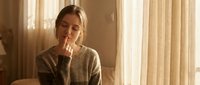 Young blonde woman in cozy sweater sitting thoughtfully by window with warm natural light, perfect for lifestyle and wellness content.