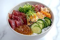 Fresh poke bowl with raw tuna, salmon roe, cucumber slices, microgreens and white rice on marble background, traditional Hawaiian cuisine.