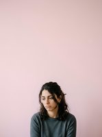 Young woman with long dark hair and fair complexion wearing gray casual t-shirt against soft pink background. Suitable for lifestyle, mental health, wellness, and portrait projects.