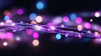 Glowing purple and blue bokeh lights with luminous curved light trails against dark background, creating magical festive atmosphere for holiday designs.
