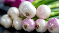 Fresh white and pink pearl onions in a row with green stems, macro food photography showing texture and natural gradient colors against dark background.