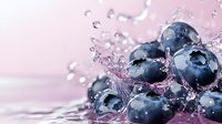 Fresh ripe blueberries with splashing water drops and dynamic motion on pink background, macro photography showing juicy berries in refreshing spray.