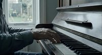 Close-up of hands playing white piano keys in cozy home setting with natural window light for music education and practice concepts.