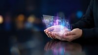 Businessman holding glowing digital hologram with financial charts and stock market data visualization on hand against blurred background for business analytics.