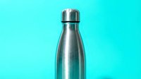 Stainless steel insulated water bottle with cap isolated on bright turquoise background, suitable for product mockups and beverage packaging designs.