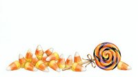 Candy corn scattered and arranged with striped lollipop on white background, isolated for Halloween designs, greeting cards, and seasonal marketing materials.