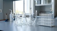 Modern laboratory workspace with glass flasks, beakers and test tubes on clean counter for scientific research and chemical analysis experiments.