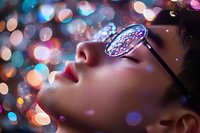 Young Asian woman wearing kaleidoscope glasses in dreamy night atmosphere with colorful bokeh lights creating magical mood for creative portrait photography.