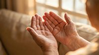 Elderly hands cupped together in prayer or meditation gesture, soft natural lighting creating peaceful spiritual moment for wellness and mindfulness concepts.