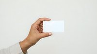 Male hand with medium skin tone holding blank white business card against neutral background, suitable for corporate branding and marketing materials.