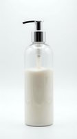 Cream-colored liquid soap or lotion in clear glass pump bottle with chrome dispenser on white background, ready for skincare, cosmetics, or bathroom product packaging design.