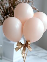 Soft pink balloons with elegant gold ribbon bow against blurred light background, creating romantic and festive party atmosphere for celebrations and events.