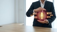 Businessman in dark suit and white shirt holding glowing lightbulb surrounded by innovation icons, representing creative solutions and strategic business development for corporate presentations.