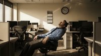 Exhausted businessman sleeping in ergonomic office chair during late work hours in modern corporate workspace with dramatic lighting.