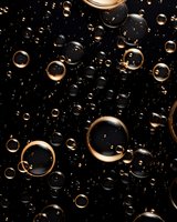 Golden and clear bubbles floating on dark background create dramatic contrast and luxurious atmosphere. Abstract macro photography for elegant design projects.