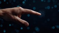 Magical finger touch creating glowing particles against dark background with blue bokeh lights, representing digital transformation and future technology concept.
