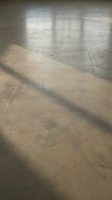 Empty concrete industrial room with natural window light casting shadows on textured floor for architectural and construction projects.