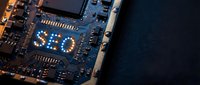 Close-up view of computer motherboard with SEO text overlay on blue circuit board showing electronic components and microchips for digital marketing concepts.