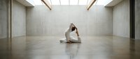 Young woman practicing yoga meditation in modern minimalist studio with natural skylight creating peaceful wellness atmosphere for mindfulness training.