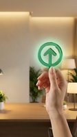 Hand holding glowing green upload arrow icon in modern office interior with warm lighting and plants for digital technology concepts.
