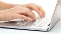 Close-up of female hands typing on white laptop keyboard against isolated background, suitable for business, technology, and office work concepts.