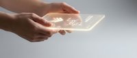 Hands holding glowing transparent digital tablet with light effects against neutral background, representing technology innovation and digital communication.
