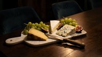 Assorted cheeses with fresh grapes and figs arranged on wooden boards, perfect for food styling, culinary content, restaurant menus, and gourmet food photography.