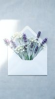 White envelope with lavender and baby's breath flowers on a soft linen background, flat lay composition for greeting cards or wedding invitations.