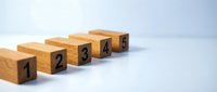 Wooden blocks numbered one through five arranged in sequence on white surface for business growth and progression concepts.
