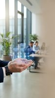 Businessman hand presenting digital network icons in modern office environment with colleagues working in background for technology concepts.