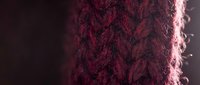 Close-up of burgundy knitted fabric texture with cable knit pattern and soft lighting, suitable for fashion, textile, and apparel design projects.