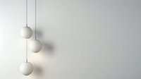 Minimalist white spherical pendant lamps hanging at different heights against light gray wall creating soft shadows and elegant modern interior design composition.