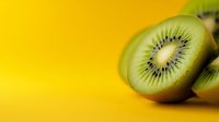 Fresh kiwi fruit slices on vibrant yellow background with copy space for healthy eating and nutrition concepts.