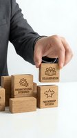Businessman hand placing wooden blocks with business concepts including collaboration, organizational efficiency and partnership success.